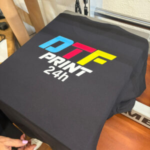 Maglietta nera personalizzata con stampa DTF colorata e brillante, pronta per essere indossata o consegnata al cliente dopo il completamento del processo di trasferimento.